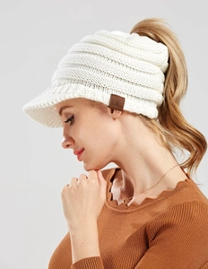 Close-up of white cable knit ponytail beanie with CC leather label and visor detail