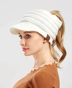 Detailed side view of white knit ponytail beanie with sun visor and C.C logo patch