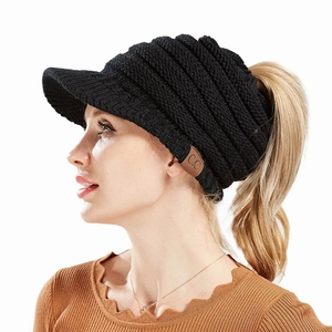 Detail of black cable knit ponytail beanie showing textured fabric and C.C brand leather patch