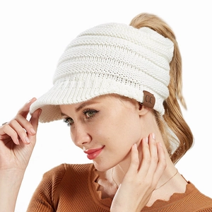 Close-up of white cable knit ponytail beanie featuring a brown leather C.C patch
