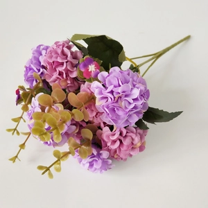 Detailed bunch of artificial hydrangea flowers in pink and purple with realistic green leaves