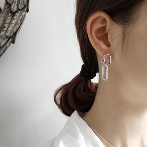 Close-up of geometric link silver earrings shown on model with polished metallic shine