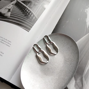 Detailed macro of 925 silver geometric hoop earrings with textured finish on a magazine