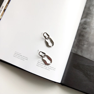 Detailed view of silver geometric hoop earrings on a high-fashion editorial magazine