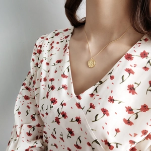 Close-up of a 925 sterling silver hammered gold pendant necklace on a female model