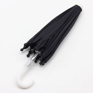Closed black doll umbrella with white curved handle and beads on white background