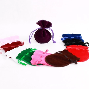 Various colors of velvet drawstring jewelry bags arranged in a circle on white background