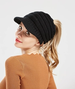 Detail of black knitted ponytail baseball cap with leather label and ribbed texture