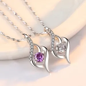 Close-up of S925 silver heart pendants with purple and clear sparkling gemstones.