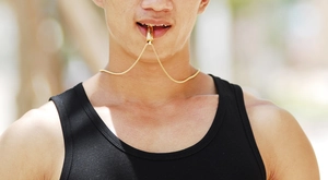 Close-up of a gold bullet urn pendant and snake chain worn by a male model