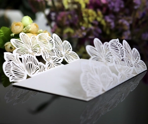 Detailed laser-cut white wedding invitation card with intricate hollow floral patterns