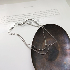 Macro shot of silver S925 layered flat bead and link chain anklet on a book