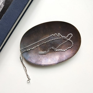Close-up of double layer S925 sterling silver anklet with flat beads on a bronze tray