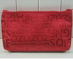 Detailed view of a red fabric makeup bag with letter jacquard and metal zipper