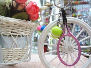 Detail shot of a pink tennis racket and yellow ball keychain hung on a basket