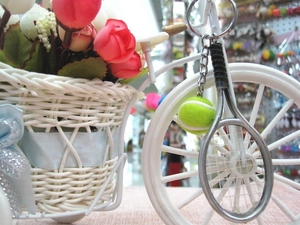 Close-up of a tennis keychain with a mini racket and fuzzy ball on a floral decor