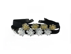 Detail of crystal flower buckle on a black elastic waist belt with metallic snap closure