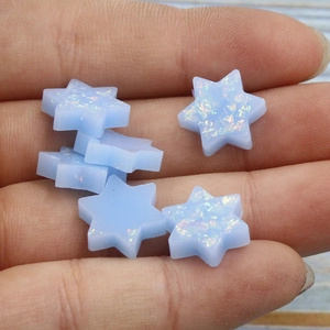Macro shot of six light blue synthetic opal Star of David pendants held by hand