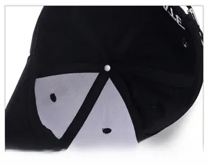 Macro detail of black cotton baseball cap interior showing white embroidery and inner lining