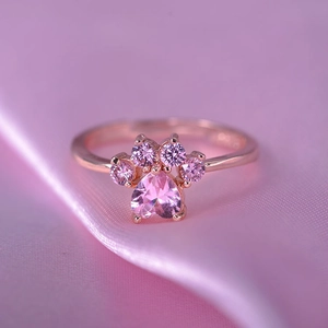 Macro detail of cat paw ring with heart-shaped pink gem and rose gold plated band