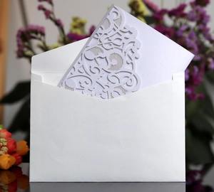 Detail of laser-cut pearl paper wedding invitation with white envelope and floral design