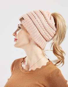 Detail of pink knitted ponytail beanie featuring a C.C leather patch and top opening