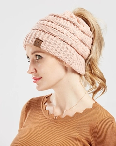 Detail of pink knitted ponytail beanie with leather label and textured yarn pattern