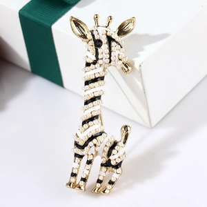 Detailed shot of an enamel giraffe brooch with pearls next to a white gift box