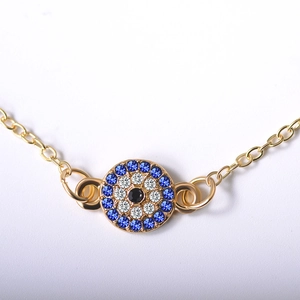 Close-up of golden anklet with evil eye pendant featuring blue and white zircon stones