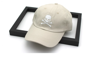 Close-up of skull and crossbones embroidery on a beige cotton twill baseball cap