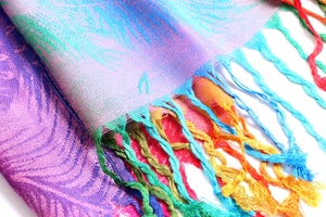 Close-up of colorful woven feather pattern and braided fringe on jacquard scarf