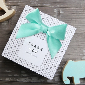 Close-up of mint green polyester satin bow on floral gift box with Thank You label