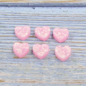 Close-up of pink heart-shaped resin charms with glitter effect for DIY jewelry making
