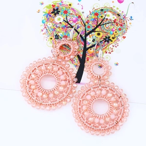 Close-up of pink handmade beaded double hoop earrings with bohemian woven texture