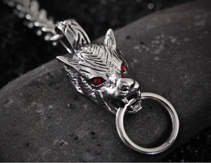 Vue macro d'un pendentif tête de loup argenté avec yeux en pierre rouge sur roche