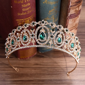 Golden bridal crown with green pear-shaped gemstones and crystals on vintage books