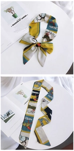 Detail of horse print silk scarf tied in a bow and laid flat on a magazine