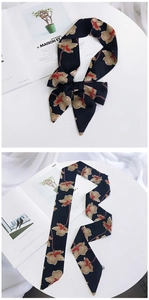 Detail of navy blue floral skinny scarf tied in a bow next to a fashion magazine