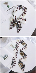 Detailed view of vintage pattern silk scarf shown tied in a bow and laid flat