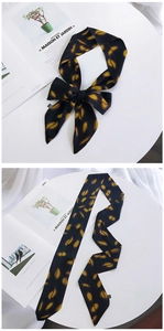 Long silk scarf with black and yellow leaf pattern shown tied as bow and flat