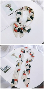 Detail showing colorful toucan and leaf print on long beige silk fashion scarf
