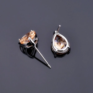 Macro shot of pear-cut champagne zircon studs in silver settings on a reflective surface