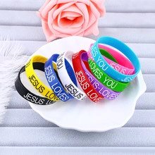 Macro shot of colorful silicone bracelets with printed Jesus Loves You text in a tray