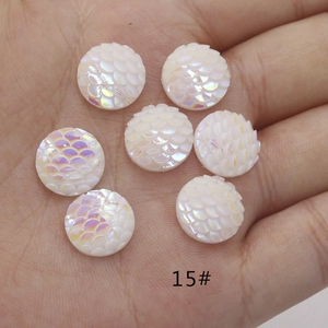 Rainbow AB resin fish scale round flatback cabochon held in hand for size display