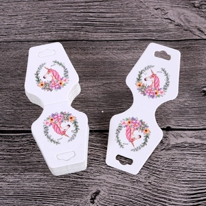 Detailed view of hourglass-shaped white jewelry display cards with unicorn design
