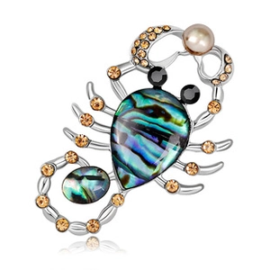 Macro view of silver scorpion brooch with abalone shell inlay and amber rhinestones