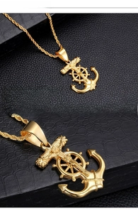 Macro detail of gold titanium cross anchor pendant on black crocodile leather texture