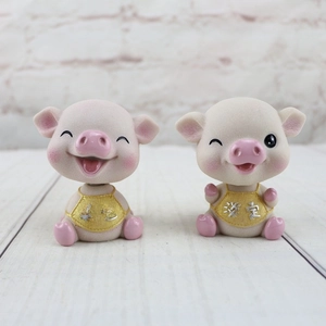 Détail de figurines de cochons en résine avec inscriptions Chance et Calme