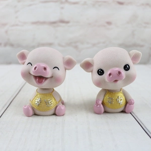 Détail de deux figurines de cochons roses en résine avec tabliers jaunes sur bois