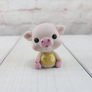 Détail d'un cochon rose en résine avec inscription Ping An dorée sur bavoir jaune